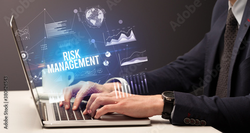 Businessman working on laptop with RISK MANAGEMENT inscription, new business concept