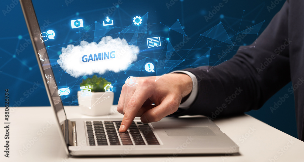 Fototapeta premium Businessman working on laptop with GAMING inscription, modern technology concept