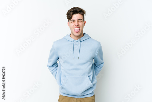Young caucasian man isolated on white background funny and friendly sticking out tongue.