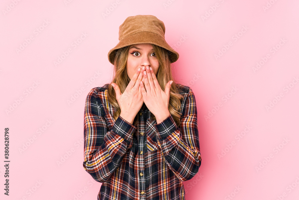 Young caucasian woman wearing a hat isolated shocked, covering mouth with hands, anxious to discover something new. Young caucasian woman wearing a hat isolated shocked, covering mouth with hands, anxious to discover something new.