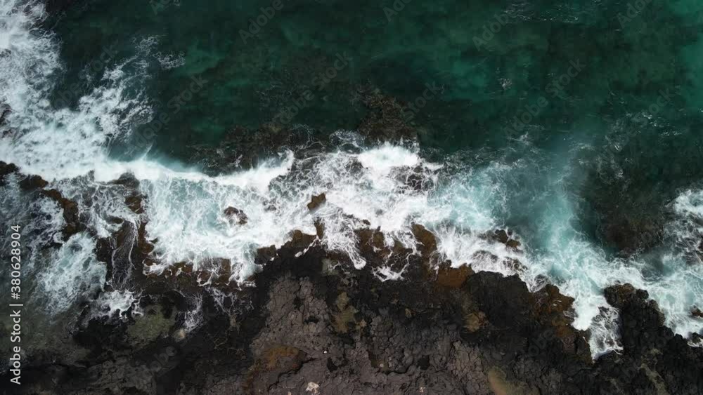 Steady view of waves crashing against lava rocks Steady view of waves crashing against lava rocks