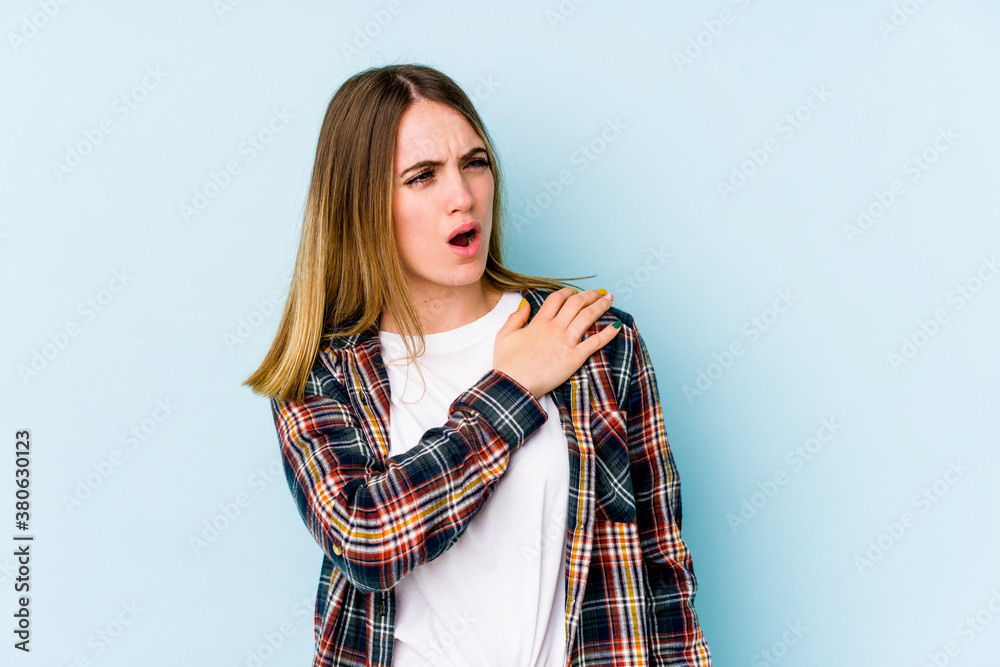 Young caucasian woman isolated on blue background having a shoulder pain. Young caucasian woman isolated on blue background having a shoulder pain.