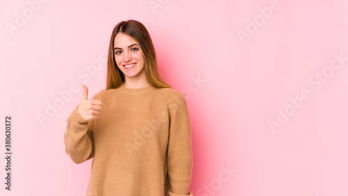Young caucasian woman isolated on pink background smiling and raising thumb up