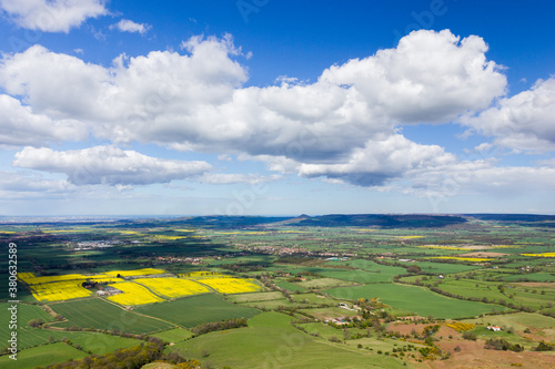 Aerial view of a green valley in Yorkshire, England on a spring day with blue skies and beautiful white clouds casting shadows on the valley.