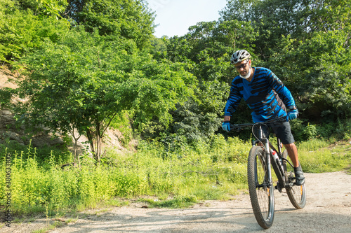 A sportsman who rides a mountain bike on a forest trail, wearing a face mask against air pollution and covid19 coronavirus. Cyclist wearing a protective mask.