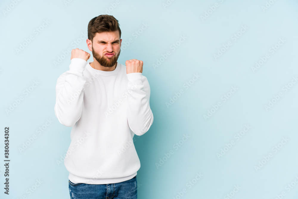 Fototapeta premium Young caucasian man isolated on blue background upset screaming with tense hands.