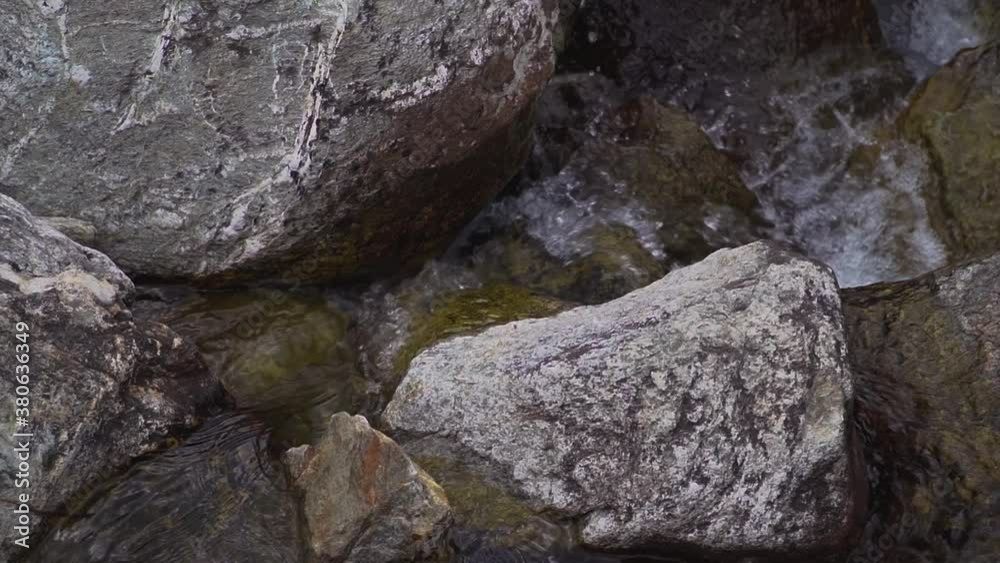Clean water runs down over grey rocks creating random splashes . Close slow motion shot. Clean water runs down over grey rocks creating random splashes . Close slow motion shot.