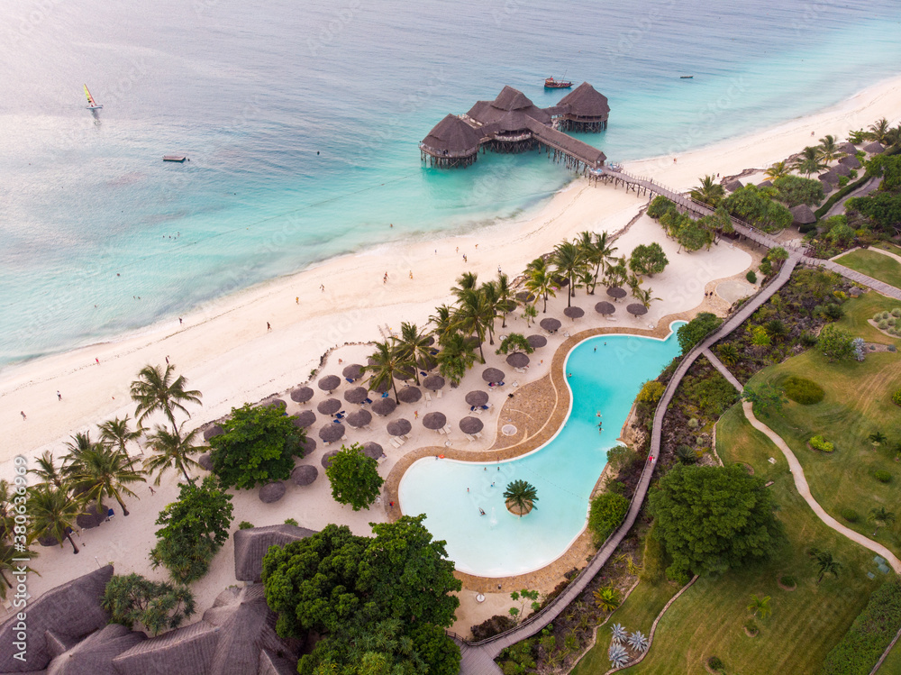 Top View on Beautiful thatch stilt house restaurant and Resort with Pool at Zanzibar Kendwa beach at evening time in Turquoise Water of Indian ocean - obrazy, fototapety, plakaty 