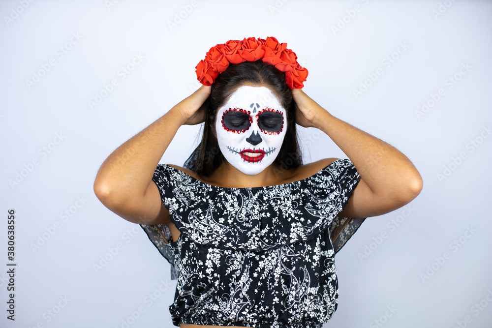 Woman wearing day of the dead costume over isolated white background suffering from headache desperate and stressed because pain and migraine with her hands on head Woman wearing day of the dead costume over isolated white background suffering from headache desperate and stressed because pain and migraine with her hands on head