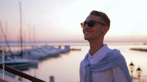 inspired man walks and looks around against summer sunset reflecting in endless sea water slow motion closeup