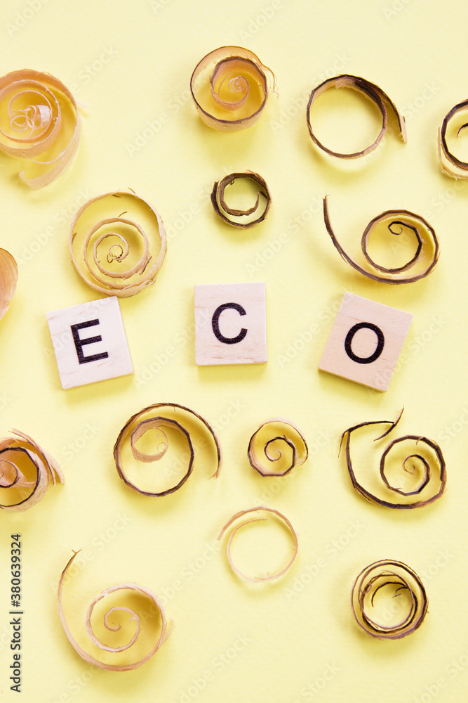 Curled shavings and word eco on yellow. Eco toys. Save the forests, awareness concept. Environmentally friendly investments. Sawdust of woodworking industry. Sawmill, carpentry Curled shavings and word eco on yellow. Eco toys. Save the forests, awareness concept. Environmentally friendly investments. Sawdust of woodworking industry. Sawmill, carpentry