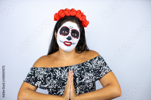 Woman wearing day of the dead costume over isolated white background begging and praying with hands together with hope expression on face very emotional and worried