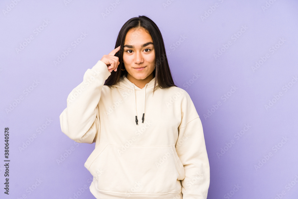 Young woman isolated on a purple background pointing temple with finger, thinking, focused on a task. Young woman isolated on a purple background pointing temple with finger, thinking, focused on a task.