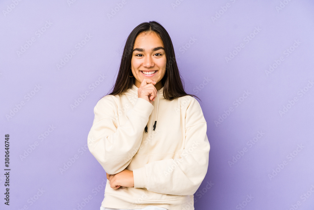 Young woman isolated on a purple background smiling happy and confident, touching chin with hand. Young woman isolated on a purple background smiling happy and confident, touching chin with hand.