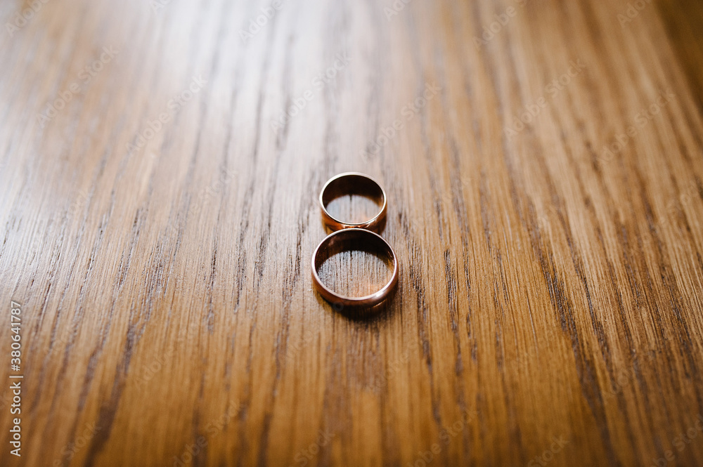 Engagement. Women's and men's rings on wooden brown background. Accessories. Top view.