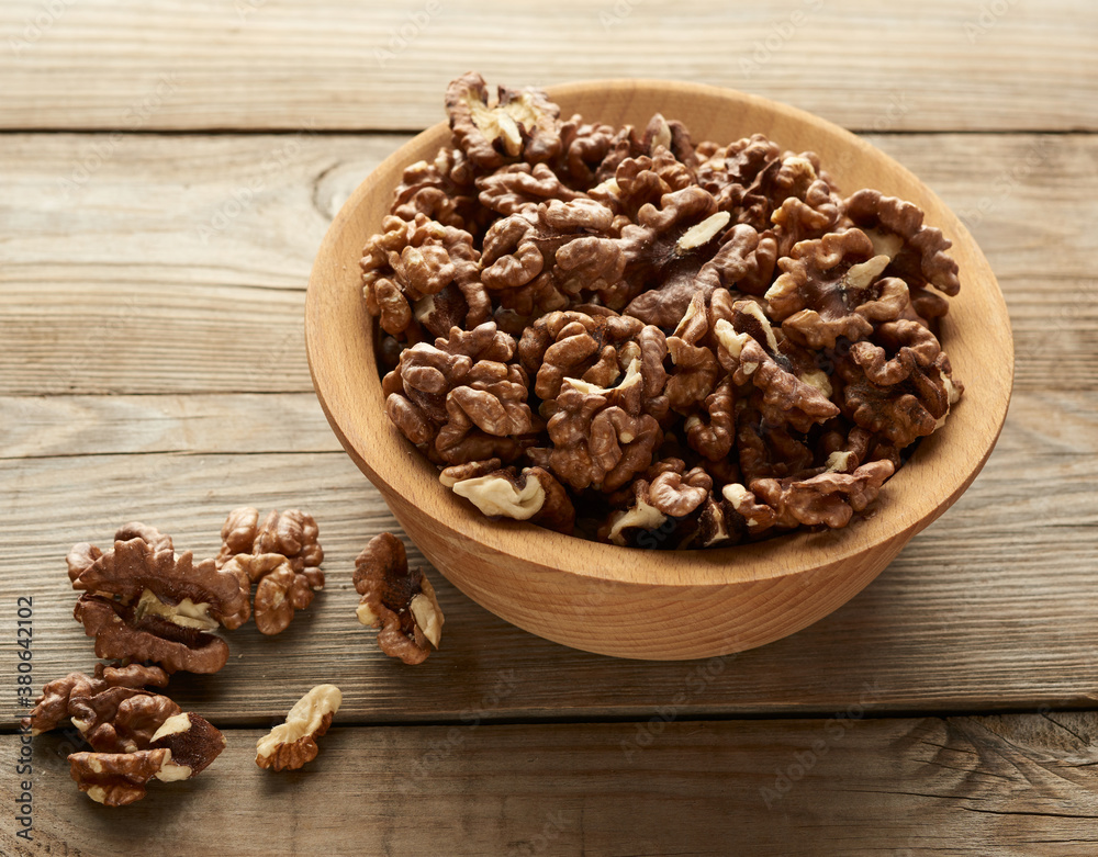 peeled walnuts in a round wooden bowl stand on a wooden table peeled walnuts in a round wooden bowl stand on a wooden table