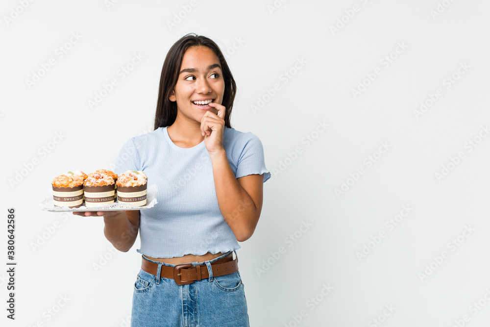 Young mixed race indian holding a sweet cakes relaxed thinking about something looking at a copy space. Young mixed race indian holding a sweet cakes relaxed thinking about something looking at a copy space.