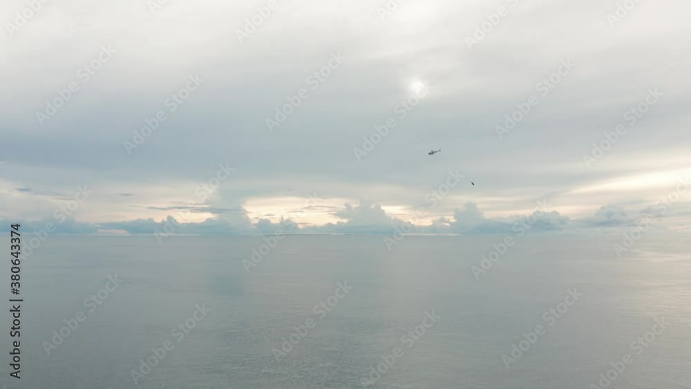 Helicopter with hanging supplies flying through air above open ocean, aerial Helicopter with hanging supplies flying through air above open ocean, aerial
