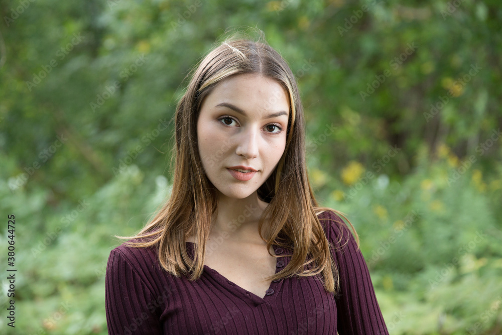 Portrait of a beautiful brunette outdoors on a green forest background. Portrait of a beautiful brunette outdoors on a green forest background.