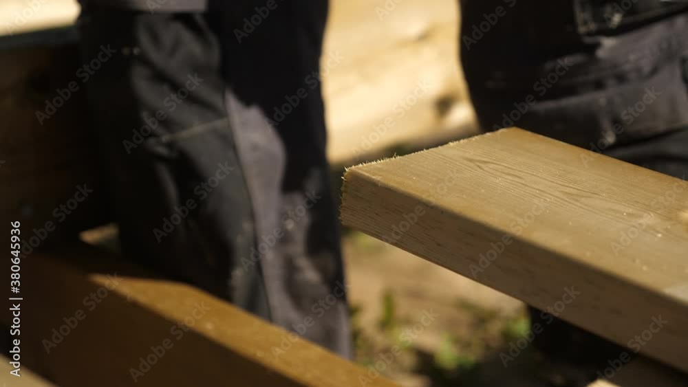 Static shot, of a carpenter, using a circular saw, to cut a deck board Static shot, of a carpenter, using a circular saw, to cut a deck board