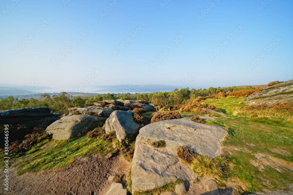 From the gritstone of Surprise View, over trees to a mist covered Derbyshire landscape