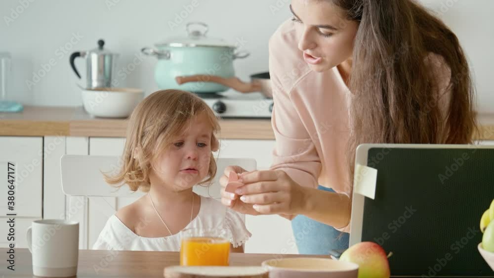 A Busy Annoyed Mother Trying to Work Remotely Calming Her Crying A Little Daughter, The Daughter Interferes With Her Mother's Work. Working From Home During Quarantine Epidemic A Busy Annoyed Mother Trying to Work Remotely Calming Her Crying A Little Daughter, The Daughter Interferes With Her Mother's Work. Working From Home During Quarantine Epidemic