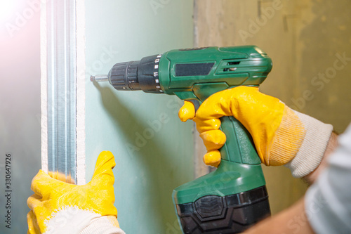 Working with drywall background. Worker hands with drill screw drywall. photo