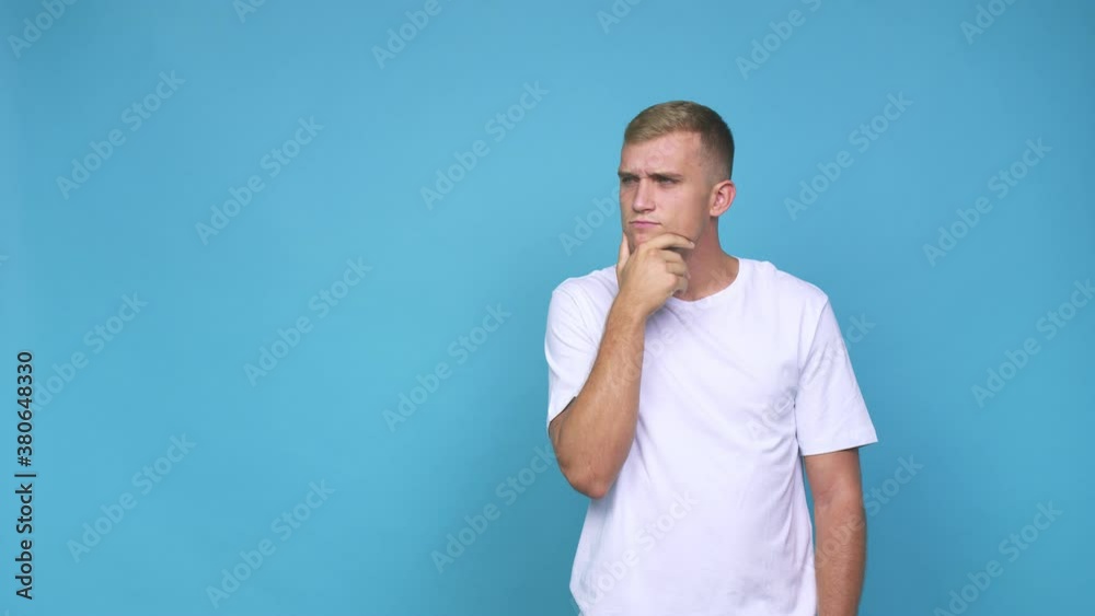 Young caucasian man looking sideways with doubtful and skeptical expression Young caucasian man looking sideways with doubtful and skeptical expression
