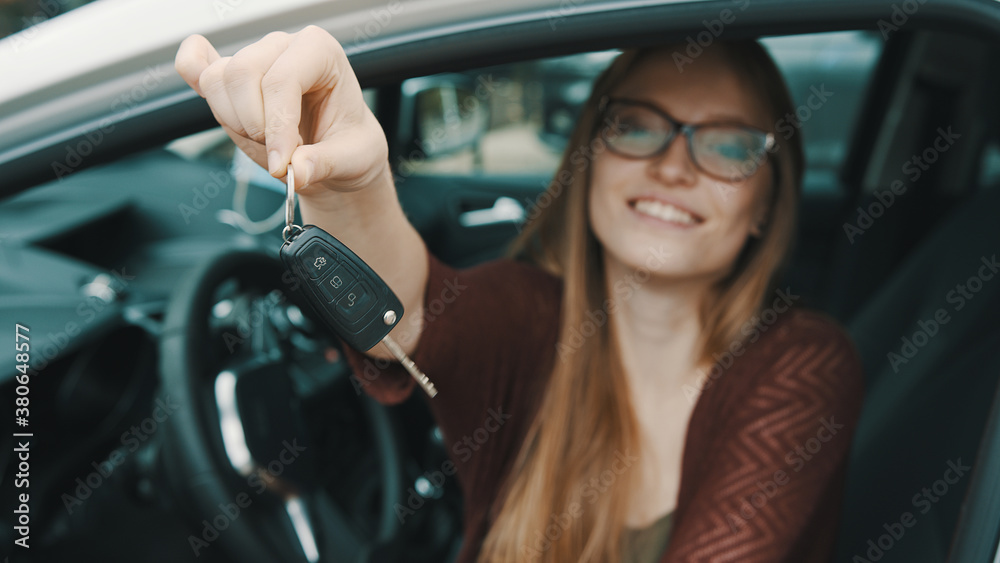 Young caucasian happy woman in front of the new car and holding keys. High quality photo
