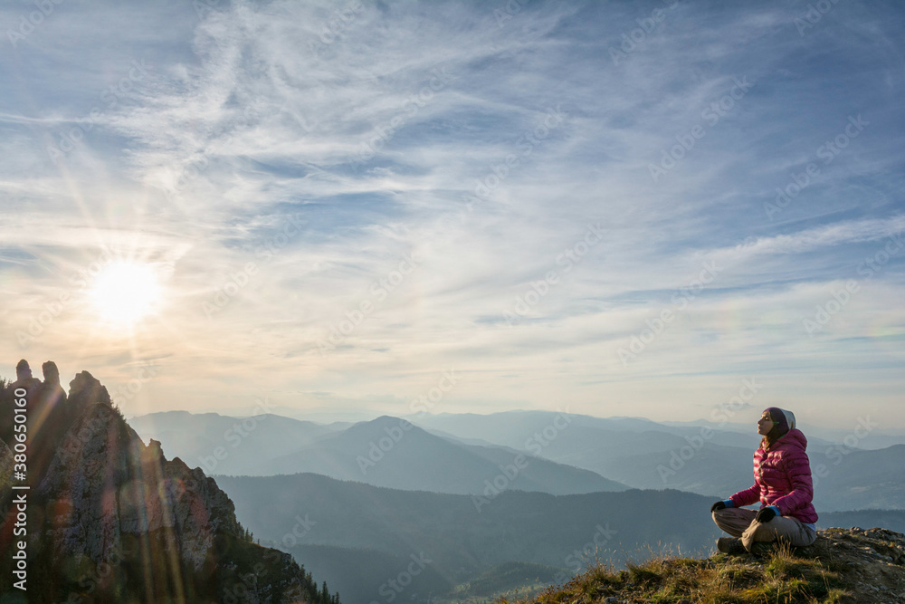 Young woman meditating on a mountain peak Young woman meditating on a mountain peak