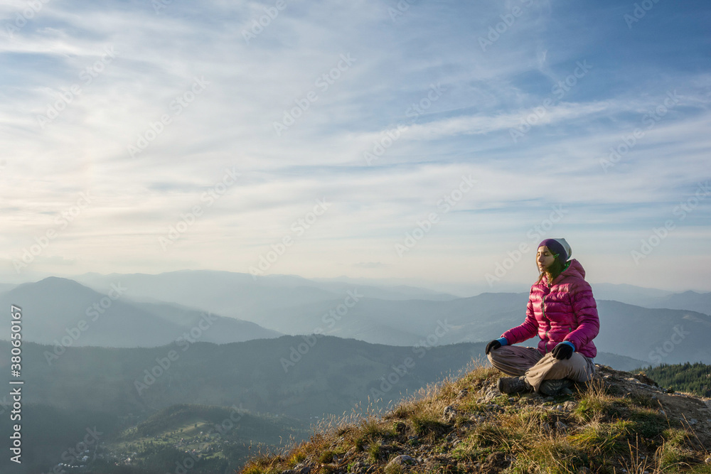 Young woman meditating on a mountain peak