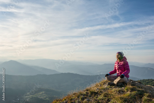 Young woman meditating on a mountain peak