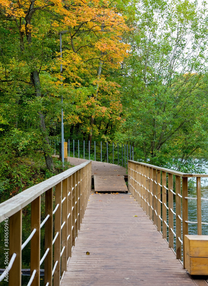 Fototapeta premium Boardwalk across the lake in autumn park
