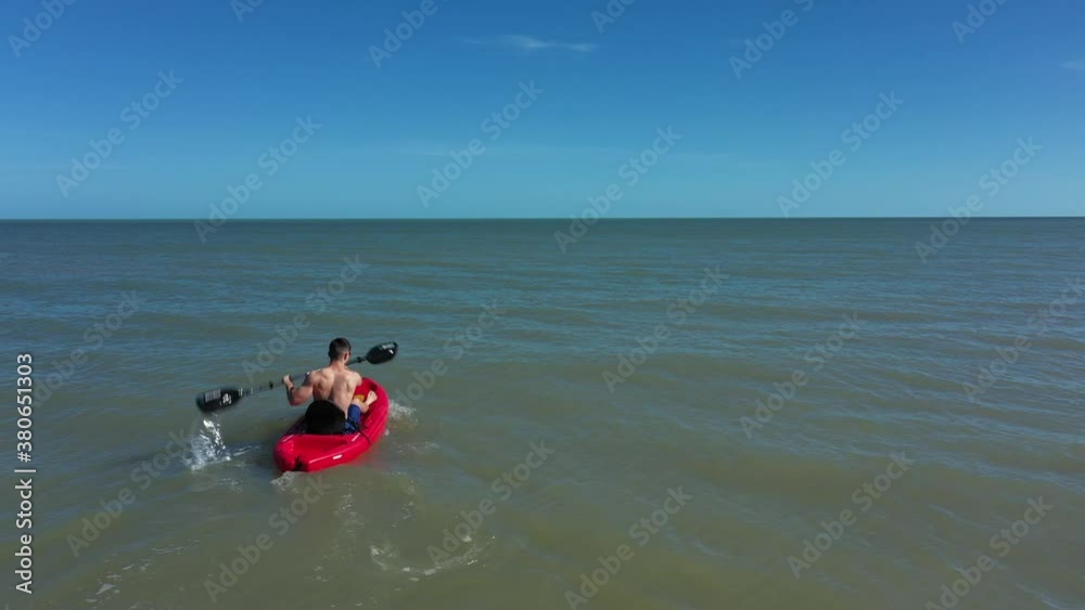 Closeup from behind of young muscular man kayaking in open water. Closeup from behind of young muscular man kayaking in open water.