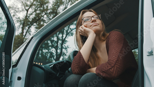 Fotografija Young caucasian woman driver with open cars door looking at the distance