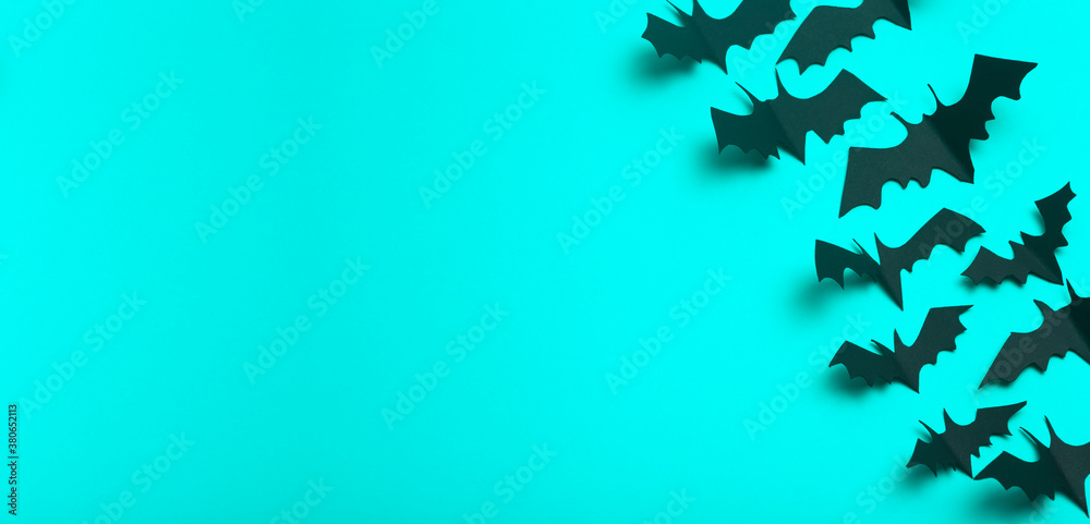 Halloween banner background. Black bats cut from paper on a blue background. Halloween decor and decorations for the holiday, copy space.