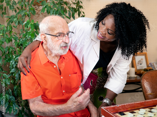 African American medical assistant holding an ederly caucasian man
