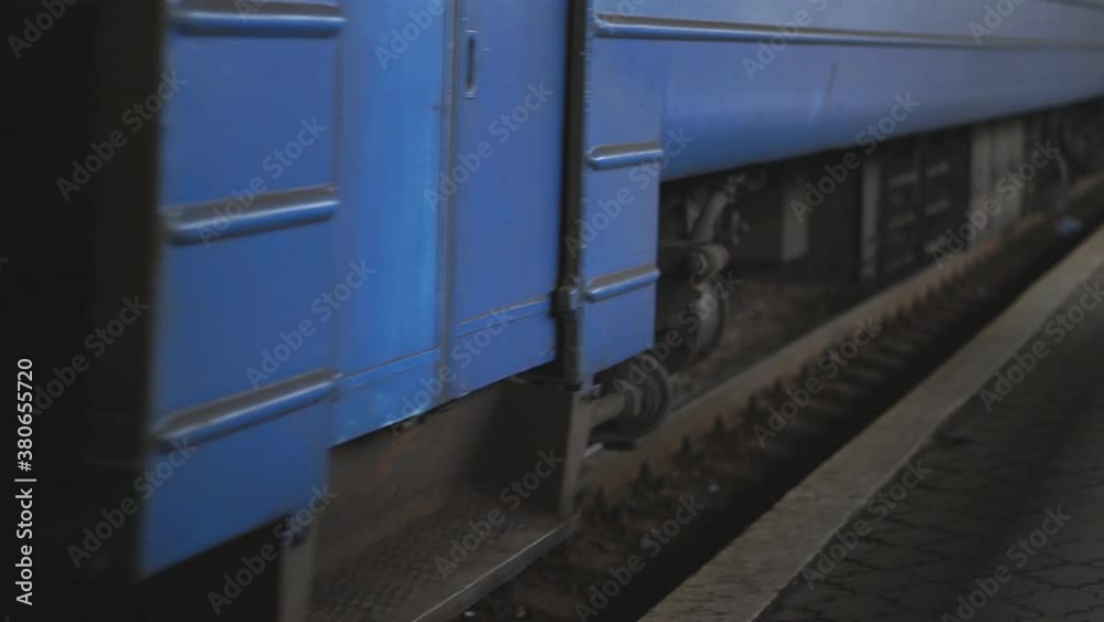Passenger railway transport passes by a camera and arrives at station. Close up spinning steel wheels of the train moving along the rail track. Concept of transportation and travel. Low view Slowmo Passenger railway transport passes by a camera and arrives at station. Close up spinning steel wheels of the train moving along the rail track. Concept of transportation and travel. Low view Slowmo