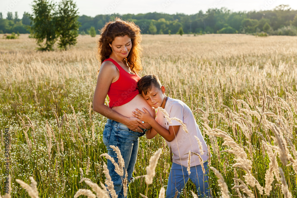 The boy is kissing the belly of his mother The boy is kissing the belly of his mother