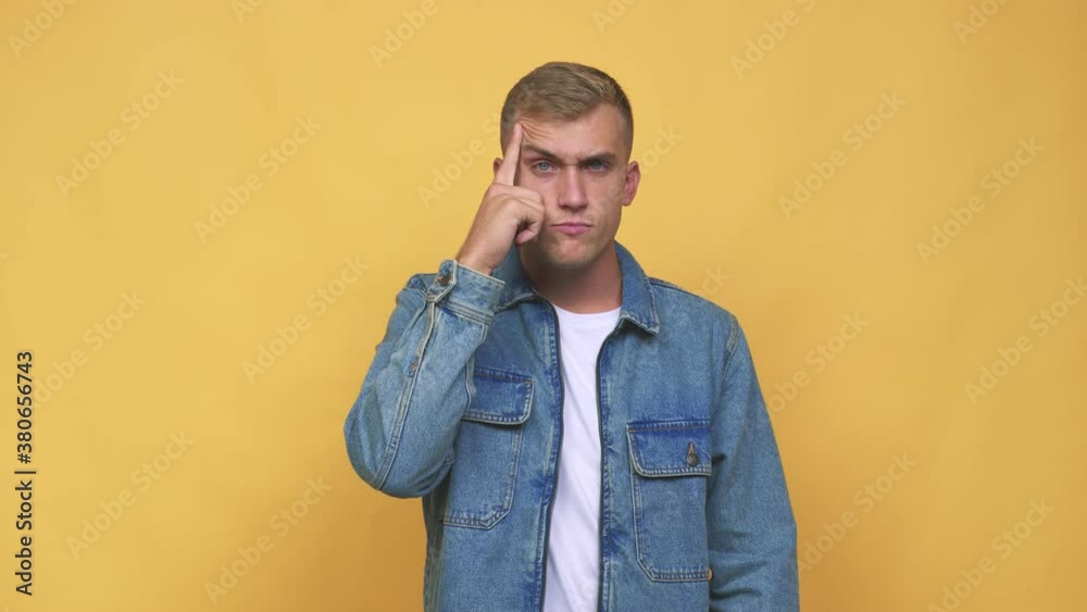 Young caucasian man pointing temple with finger, thinking, focused on a task Young caucasian man pointing temple with finger, thinking, focused on a task