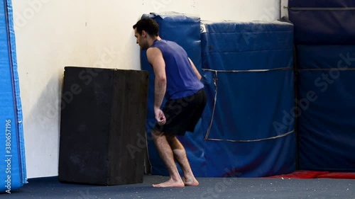 a still shot of a guy in a gymnastics gym doing high jumps to a box
from a back view photo