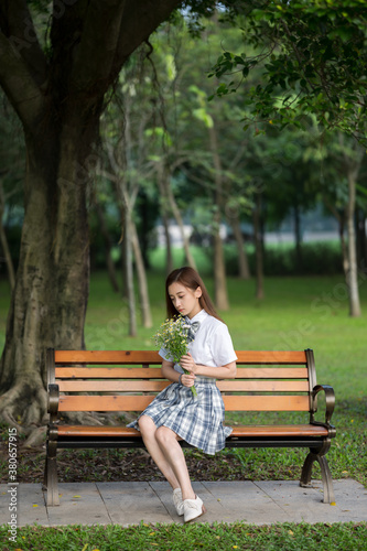 A young woman sits on a bench in the garden.