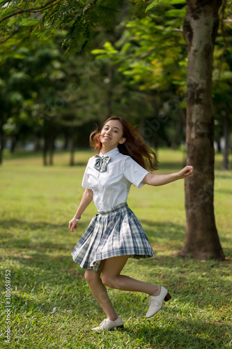 A happy young woman runs on grassland.
