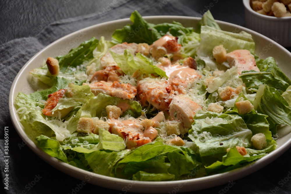 Caesar Salad with grilled chicken, Cheese and Croutons with lettuce, on plate. Grilled chicken breasts and fresh vegetables in plate. Caesar Salad with grilled chicken, Cheese and Croutons with lettuce, on plate. Grilled chicken breasts and fresh vegetables in plate.