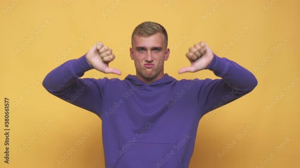 Young caucasian man showing thumb down and expressing dislike Young caucasian man showing thumb down and expressing dislike