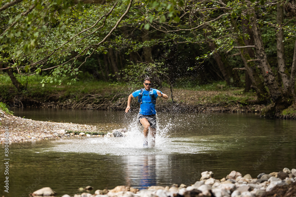 Young man in sports equipment running in mountain river Young man in sports equipment running in mountain river