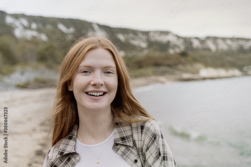 Portrait woman with red hair on beach in winter Portrait woman with red hair on beach in winter