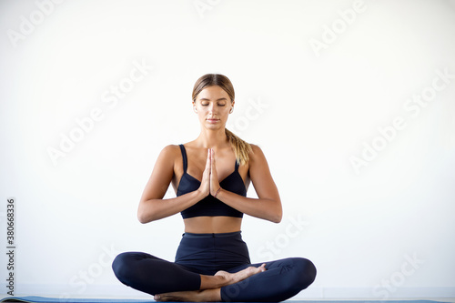 Calm pretty woman doing yoga exercise isolated on white background.