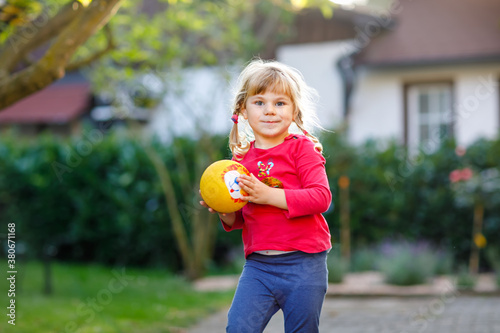 Little adorable toddler girl playing with ball outdoors. Happy smiling child catching and throwing, laughing and making sports. Active leisure with children and kids.