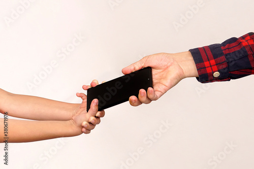 father takes the phone from his daughter. Children's addiction to mobile games. A thief stole a child's phone. Smartphone in arms close up. Passing a gift from hand to hand. photo